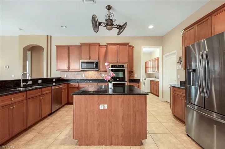 Huge kitchen with center island, lots of cabinets, stainless steel appliances and custom ceiling fan.