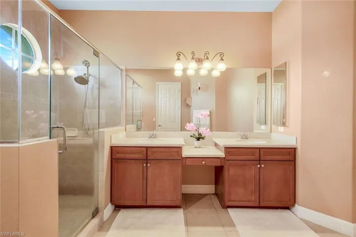 Primary bathroom featuring dual vanity and large walk-in shower with glass doors.