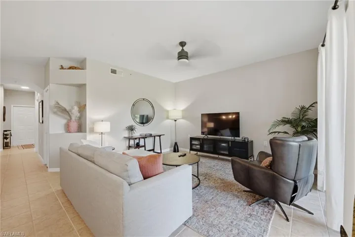 Living area featuring tile flooring, neutral wall paint, a built-in recessed wall niche, and a ceiling-mounted fan