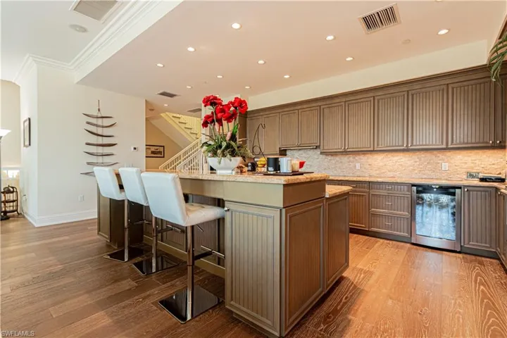 Kitchen featuring light wood finished floors, a center island with sink, visible vents, and a kitchen breakfast bar