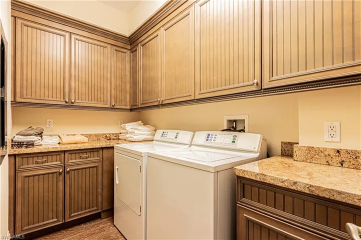 Clothes washing area featuring light wood-type flooring, cabinet space, and washer and dryer