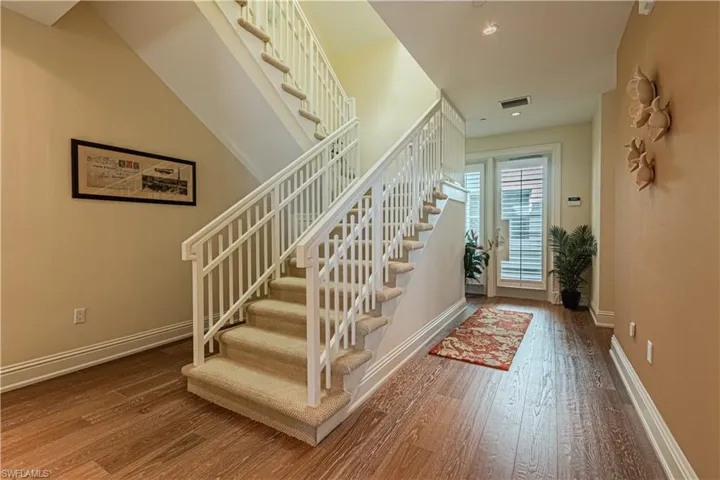Foyer entrance featuring hardwood / wood-style flooring, visible vents, stairs, and baseboards