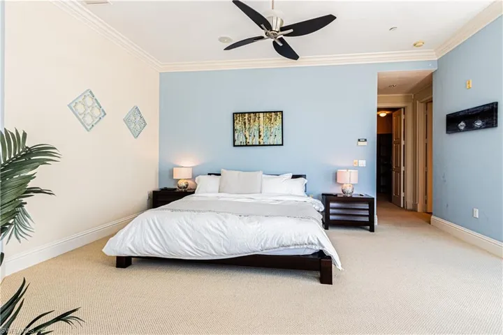 Bedroom with light carpet, a ceiling fan, baseboards, and crown molding