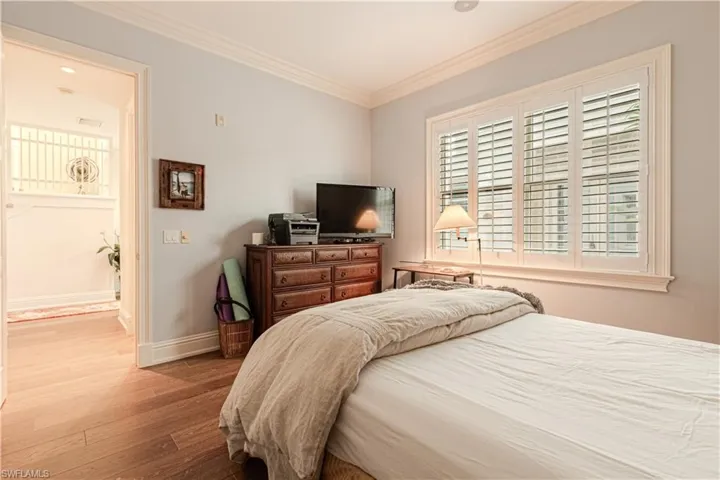 Bedroom featuring baseboards, visible vents, ornamental molding, and wood finished floors