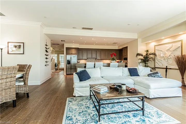 Living room featuring dark wood-style flooring, visible vents, crown molding, and baseboards