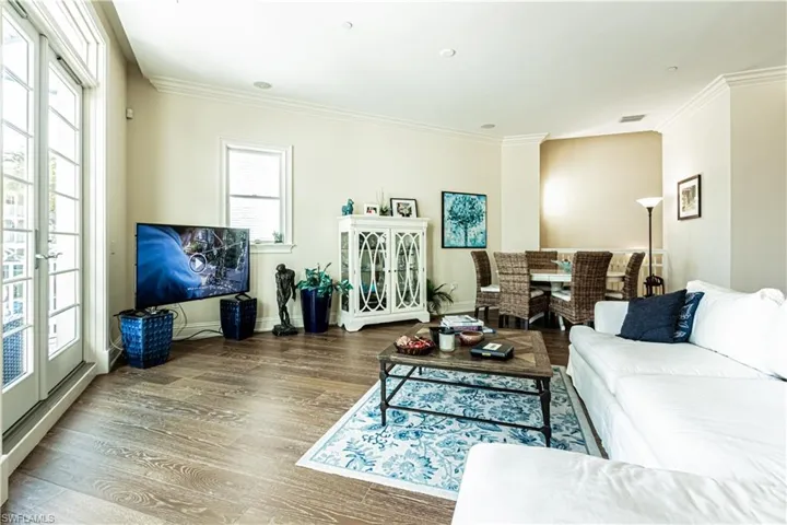 Living area featuring visible vents, crown molding, baseboards, and wood finished floors