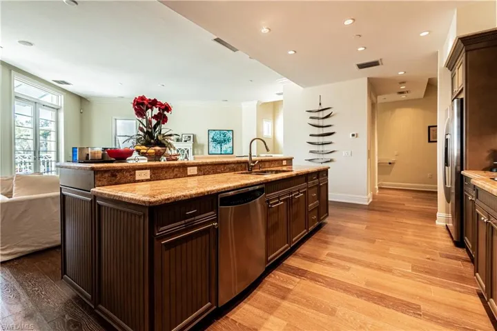 Kitchen with stainless steel appliances, visible vents, light wood-style floors, open floor plan, and a sink