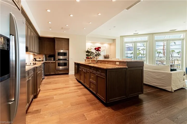 Kitchen with dark brown cabinetry, decorative backsplash, light wood-style flooring, stainless steel appliances, and french doors