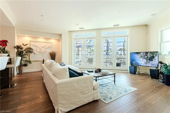Living room with baseboards, wood finished floors, visible vents, and crown molding