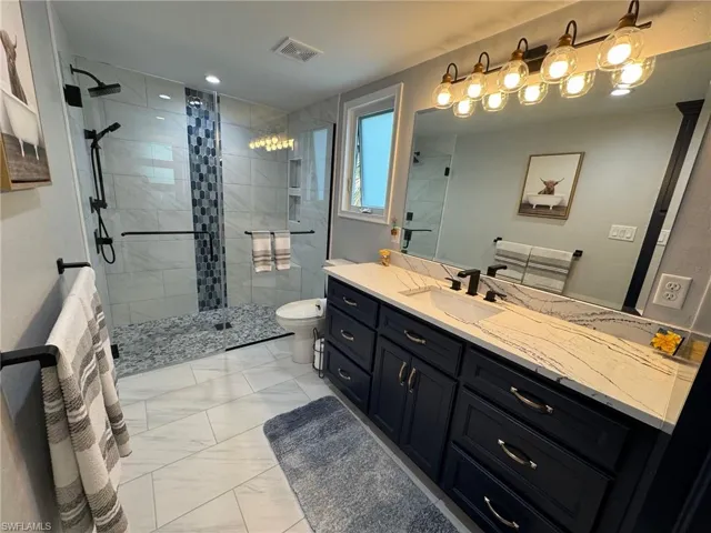 Bathroom featuring vanity, toilet, and an enclosed shower