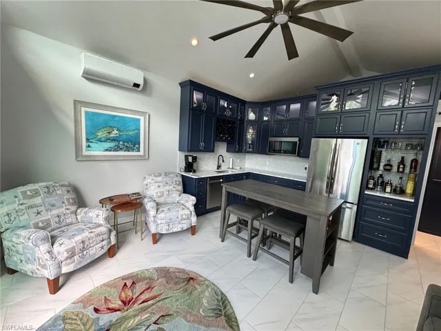 Sitting room with a wall mounted AC, ceiling fan, lofted ceiling with beams, and sink