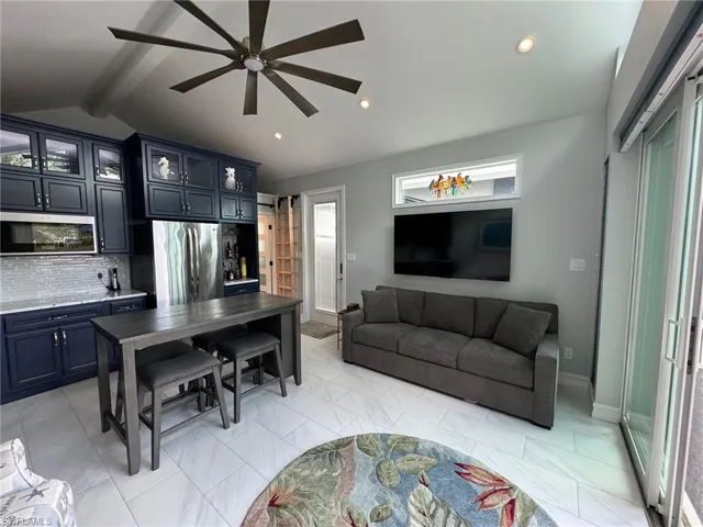 Living room featuring ceiling fan and lofted ceiling with beams