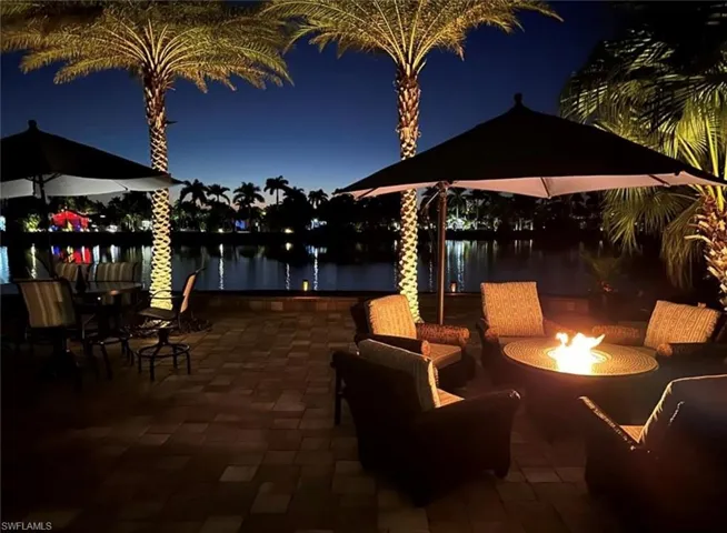 Patio at night with an outdoor fire pit and a water view