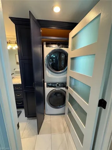 Washroom with stacked washer / dryer and light tile patterned flooring