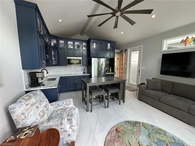Living room with ceiling fan, beamed ceiling, and sink