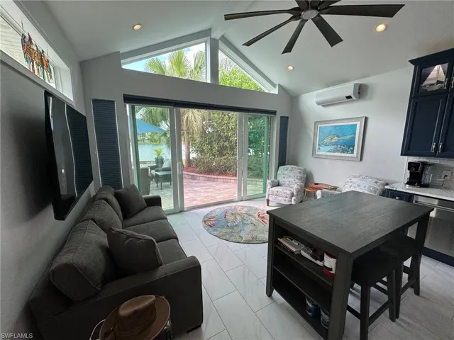 Tiled living room featuring high vaulted ceiling, an AC wall unit, ceiling fan, and beamed ceiling