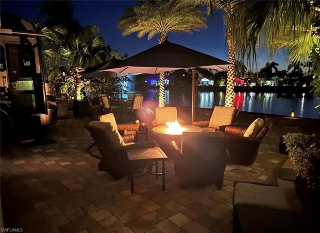 Patio at night featuring a water view and an outdoor fire pit