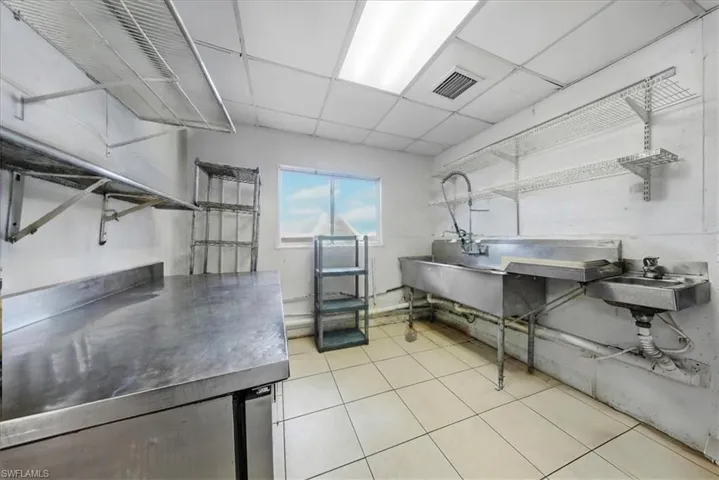 Kitchen featuring stainless steel countertops, a drop ceiling, and open shelves