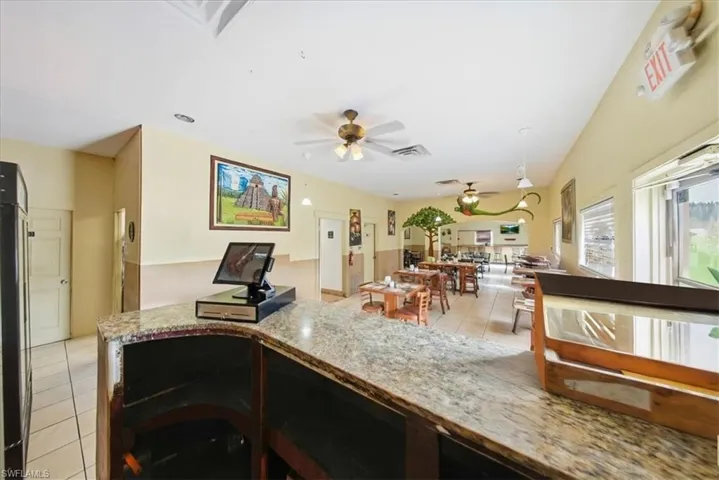 Kitchen featuring light stone counters, ceiling fan, and fridge