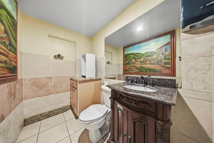 Half bathroom with tile walls, vanity, and light tile patterned floors