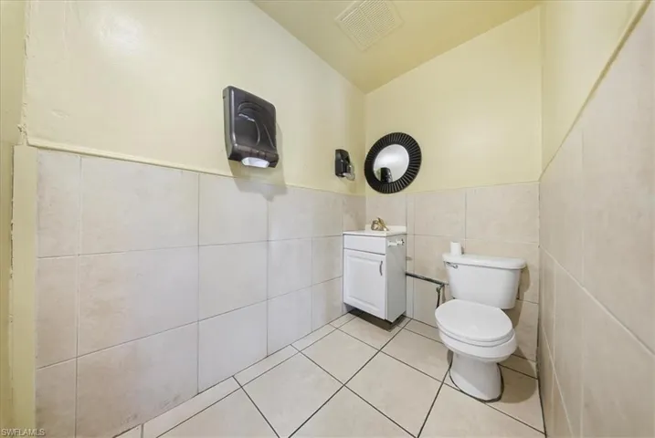 Bathroom featuring vanity, light tile patterned floors, tile walls, and wainscoting