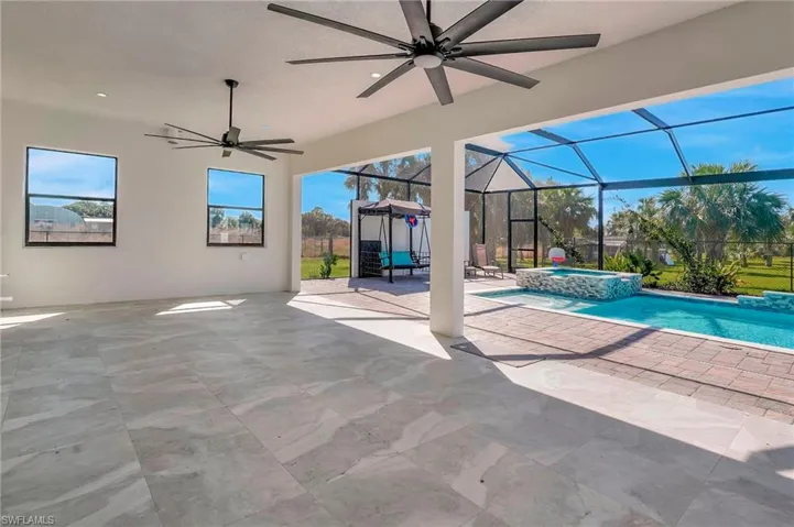 View of swimming pool with glass enclosure, a pool with connected hot tub, a ceiling fan, and a patio
