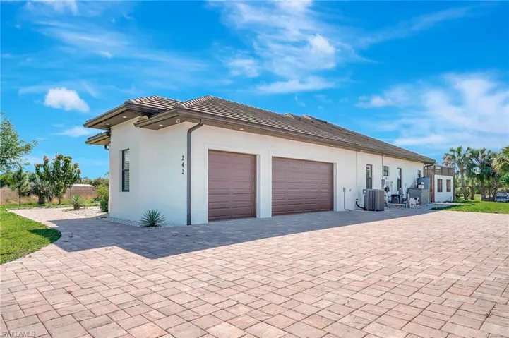 View of home's exterior featuring stucco siding, decorative driveway, cooling unit, an attached garage, and a tiled roof