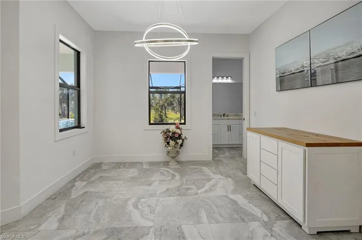 Unfurnished dining area featuring baseboards, a notable chandelier, and marble finish floor