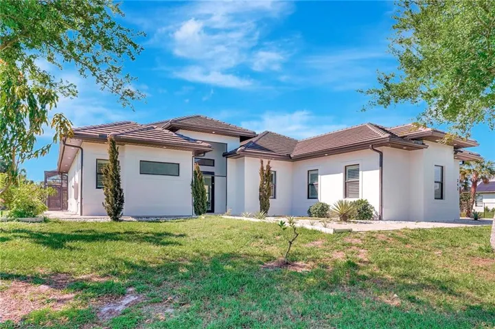 View of front of home featuring a front yard, a tiled roof, and stucco siding