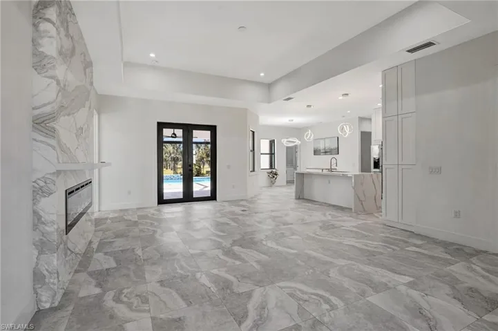 Unfurnished living room with visible vents, a sink, french doors, a fireplace, and a raised ceiling