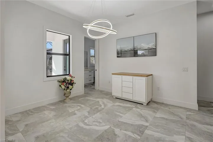 Unfurnished dining area featuring an inviting chandelier, visible vents, baseboards, and marble finish floor