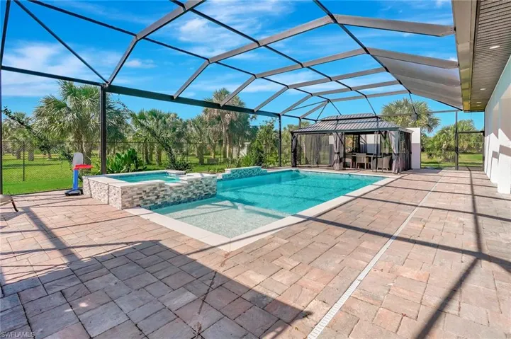 View of swimming pool with glass enclosure, a patio, and a pool with connected hot tub