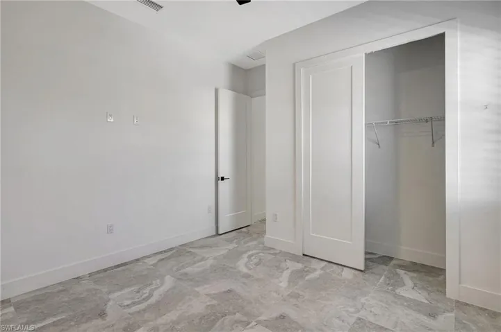 Unfurnished bedroom featuring marble finish floor, baseboards, and a closet