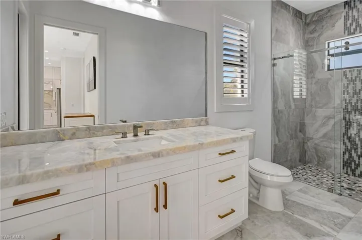 Bathroom featuring toilet, a healthy amount of sunlight, a stall shower, and vanity