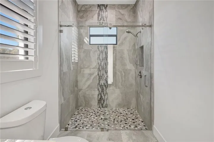 Bathroom with a stall shower, toilet, and baseboards