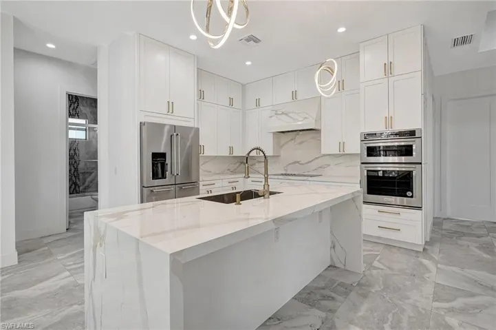 Kitchen with a sink, visible vents, appliances with stainless steel finishes, and under cabinet range hood