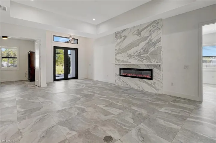 Unfurnished living room featuring plenty of natural light, french doors, and a fireplace