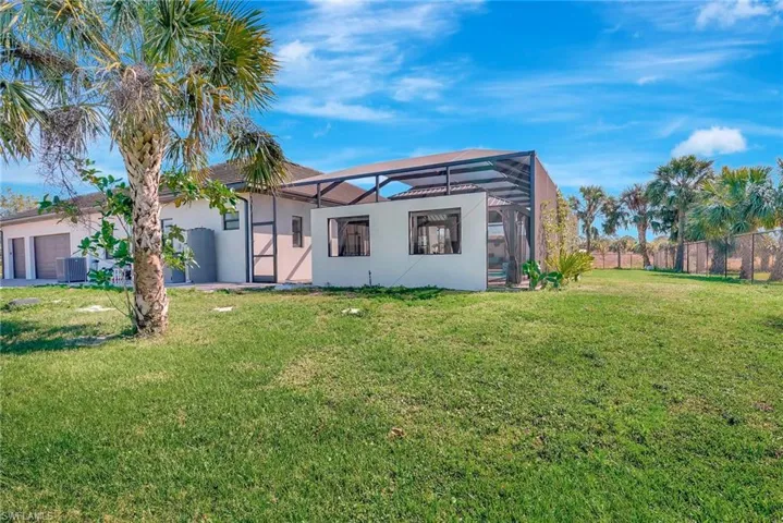 Back of house featuring fence, a lanai, central air condition unit, stucco siding, and an attached garage