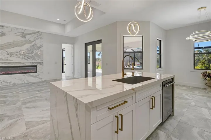Kitchen with marble finish floor, pendant lighting, a sink, a fireplace, and light stone countertops