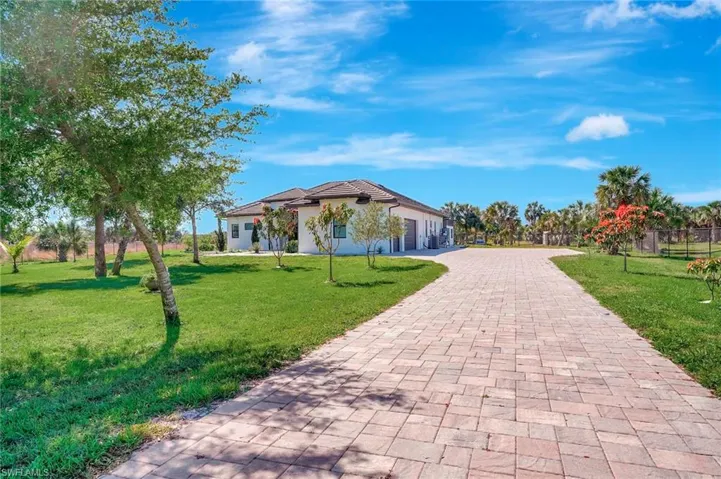 Surrounding community with decorative driveway, fence, a garage, and a yard