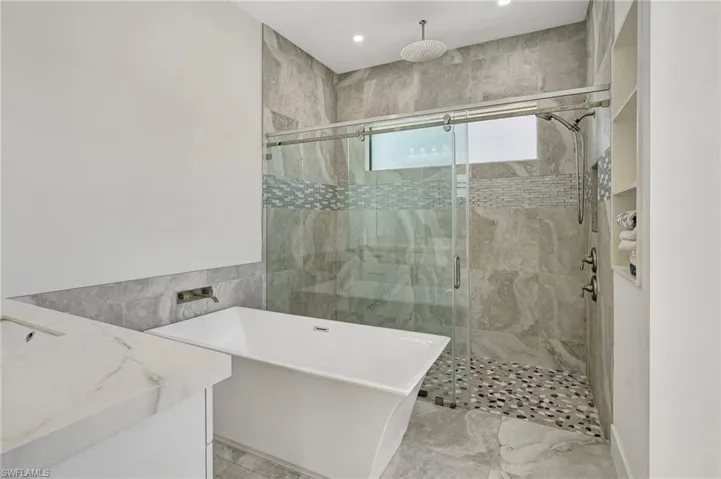 Bathroom featuring a shower stall, vanity, recessed lighting, a soaking tub, and tile walls