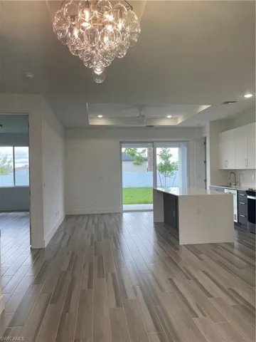 Unfurnished living room featuring a tray ceiling, light wood-style floors, a chandelier, and recessed lighting