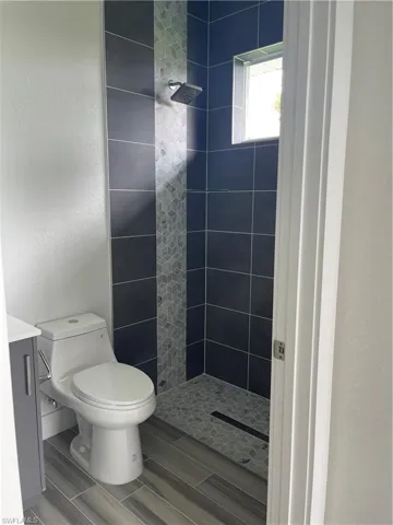 Bathroom featuring a shower stall, a textured wall, vanity, and wood finish floors
