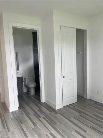 Bedroom with wood tiled floors, a closet, and connected bathroom