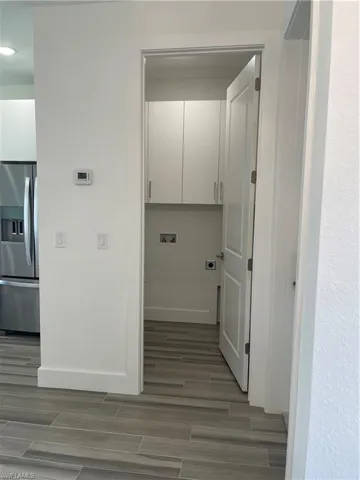 Laundry area with hookup for an electric dryer, wood tiled floors, cabinet space, and hookup for a washing machine