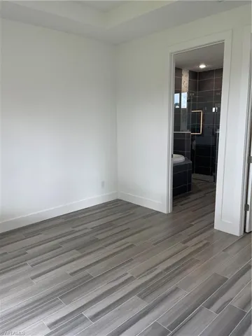 Unfurnished room featuring dark wood-style flooring and baseboards