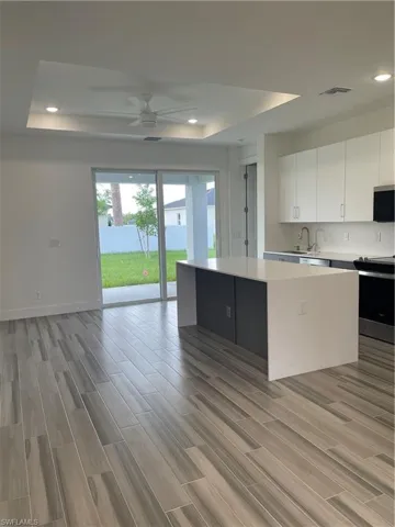 Kitchen with a raised ceiling, light wood finished floors, open floor plan, stainless steel range, and a center island