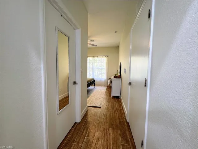Primary bedroom view from primary bathroom. Walk-in closet to left and bedroom door to right.