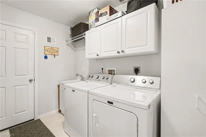 Spacious laundry room includes sink, cabinets and shelving
