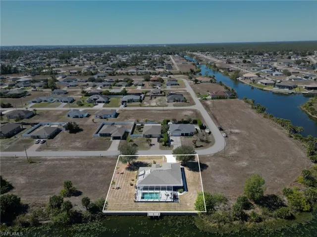 Aerial perspective of suburban area with property parcel outlined and a nearby body of water